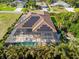 Aerial view of a well-maintained home featuring solar panels and an enclosed pool surrounded by lush greenery at 329 Myrtle Ave, Nokomis, FL 34275