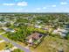 An aerial view of a home with lush landscaping, a paved driveway, and manicured lawns under a blue sky with puffy clouds at 329 Myrtle Ave, Nokomis, FL 34275