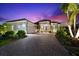 Elegant single-story home featuring a tile roof, paver driveway, attached two-car garage, and well-maintained landscaping at twilight at 329 Myrtle Ave, Nokomis, FL 34275