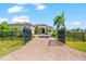 Beautifully landscaped home featuring a paver driveway, black fence, and mature palm trees at 329 Myrtle Ave, Nokomis, FL 34275