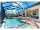 Screened-in pool with attached spa, waterfall feature, outdoor kitchen, and an outdoor seating area at 329 Myrtle Ave, Nokomis, FL 34275