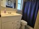 Bathroom features a white vanity, sink, toilet, and shower with blue shower curtain at 3311 Papaya Rd, Venice, FL 34293