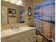 Bathroom with a white vanity, sink, seashell decorations, and a shower with ocean themed curtain at 3311 Papaya Rd, Venice, FL 34293