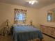 Bedroom featuring a blue comforter with floral curtains, bedside lamps, and light colored dresser at 3311 Papaya Rd, Venice, FL 34293