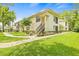 Exterior of a charming two-story home with lush green lawn, garden, and stairs leading to the upper level at 3382 Mermoor Dr # 3102, Palm Harbor, FL 34685
