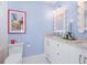Airy bathroom featuring dual sinks, white cabinets, marble countertop, decorative mirror, and light blue walls at 3516 Casey Key Rd, Nokomis, FL 34275