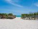This idyllic beach access features a wooden walkway to the ocean, with lush greenery lining the path to the sandy shore at 3516 Casey Key Rd, Nokomis, FL 34275