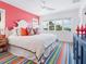 Bright bedroom featuring a ceiling fan, pink accent wall, with a large plush bed and tropical-themed pillows at 3516 Casey Key Rd, Nokomis, FL 34275
