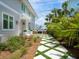 Beautiful home exterior highlighting a lush walkway that connects the side yard to the patio, showcasing tropical landscaping at 3516 Casey Key Rd, Nokomis, FL 34275