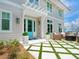 A beautiful home entrance featuring a turquoise door, manicured landscaping, a cozy seating area, and a unique grass paver driveway at 3516 Casey Key Rd, Nokomis, FL 34275
