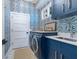 Chic laundry room showcasing modern appliances, stylish blue cabinetry, and eye-catching patterned wallpaper at 3516 Casey Key Rd, Nokomis, FL 34275
