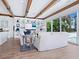 Open living room with built-in shelving, wood beam ceiling, and sliding glass doors to outdoor patio and pool at 3516 Casey Key Rd, Nokomis, FL 34275