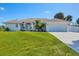 Charming single-story home featuring a manicured lawn and a pristine driveway leading to an attached two-car garage at 381 La Playa Ln, Port Charlotte, FL 33953
