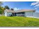 Well-maintained home features a spacious backyard with lush green grass and screened-in lanai, perfect for outdoor entertaining at 381 La Playa Ln, Port Charlotte, FL 33953