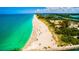 Stunning aerial view of the coastline, with beachgoers enjoying the clear turquoise water and sandy beach at 3950 Pepper Ln, North Port, FL 34287