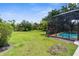 Expansive backyard with a screened-in pool area, lush greenery, and ample space for outdoor activities at 3950 Pepper Ln, North Port, FL 34287