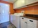 This laundry room has white cabinets, a utility sink, washer and dryer, plus durable slate floors at 4103 Kinlock St, North Port, FL 34286