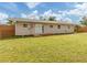 View of the house from a spacious backyard with a sliding glass door and deck at 4192 Tarpon Rd, Venice, FL 34293