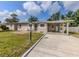 Exterior of a one-story home with a green lawn, carport, and a cozy outdoor seating area at 4192 Tarpon Rd, Venice, FL 34293