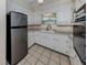 A quaint kitchen with white cabinets, a stainless-steel refrigerator, and a bright window at 4192 Tarpon Rd, Venice, FL 34293