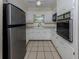 A compact kitchen featuring white cabinets, a stainless-steel refrigerator, and tiled flooring at 4192 Tarpon Rd, Venice, FL 34293