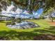 Scenic view of the pond reflecting clouds alongside lush golf course and nearby condominiums at 421 Cerromar Ter # 471, Venice, FL 34293