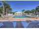 Stunning community pool surrounded by lounge chairs, palm trees, and lush greenery, offering a resort-like experience at 421 Cerromar Ter # 471, Venice, FL 34293