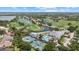 Expansive aerial view of a community featuring a golf course, tennis courts, swimming pool, and scenic water views at 427 Autumn Chase Dr, Venice, FL 34292
