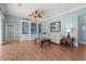 Comfortable living room with custom built-in shelving, a ceiling fan, and wood floors with accent lighting at 427 Autumn Chase Dr, Venice, FL 34292