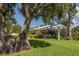 Beautiful landscaped backyard features a white pergola with pink flowering vines, perfect for outdoor relaxation at 463 Park Trace Blvd, Osprey, FL 34229
