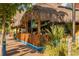 Tropical outdoor dining area with a thatched roof, bamboo fence, and lush greenery along a scenic street at 463 Park Trace Blvd, Osprey, FL 34229