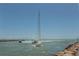 A sailboat under a clear blue sky cruising along the ocean with a rocky shore on the left at 463 Park Trace Blvd, Osprey, FL 34229