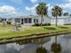 Waterfront home with lush lawn, palm trees and an enclosed porch at 485 Schooner St, North Port, FL 34287