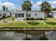 Waterfront home with lush lawn, palm trees and an enclosed porch at 485 Schooner St, North Port, FL 34287