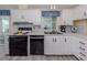 Well-lit kitchen with white cabinets, black appliances, and a double-basin sink beneath a window at 485 Schooner St, North Port, FL 34287