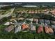 Aerial view of a terracotta-roofed home nestled in a residential community surrounded by lush trees and modern buildings at 4912 Bella Terra Dr, Venice, FL 34293