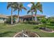 Well-manicured backyard featuring a screen-enclosed patio, lush lawn, and beautiful landscaping with mature palm trees at 4912 Bella Terra Dr, Venice, FL 34293