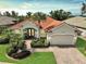 Charming single-story home featuring a red tile roof, mature landscaping, and a paved driveway and walkway at 4912 Bella Terra Dr, Venice, FL 34293