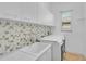 Laundry room has white cabinets and an elegant mosaic backsplash over the sink at 4912 Bella Terra Dr, Venice, FL 34293