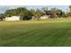 Expansive backyard with luscious lawn and mature trees with outbuildings and a pond in the distance at 5760 Howard Creek Rd, Sarasota, FL 34241