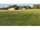 Expansive backyard with luscious lawn and mature trees with outbuildings and a pond in the distance at 5760 Howard Creek Rd, Sarasota, FL 34241