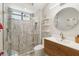Modern bathroom with a glass-enclosed shower, wood vanity, and round mirror offering a spa-like experience at 5850 Saddle Oak Trl, Sarasota, FL 34241