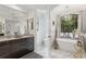Modern bathroom with marble countertops, stylish vanity, separate toilet room and soaking tub by a window at 5850 Saddle Oak Trl, Sarasota, FL 34241