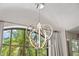 Close-up of a modern chandelier with an arch window that offers plenty of natural light at 5850 Saddle Oak Trl, Sarasota, FL 34241
