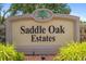 Saddle Oak Estates sign with a decorative tree emblem surrounded by lush greenery at 5850 Saddle Oak Trl, Sarasota, FL 34241