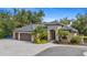 Beautiful home showcasing a paver driveway, three-car garage, and meticulously landscaped yard with palm trees and colorful flowers at 5850 Saddle Oak Trl, Sarasota, FL 34241