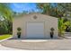 A standalone garage with a neutral color, adorned with a decorative compass rose and potted plants at 5850 Saddle Oak Trl, Sarasota, FL 34241