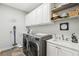 Functional laundry room with modern washer and dryer, ample cabinet space, and a utility sink at 5850 Saddle Oak Trl, Sarasota, FL 34241