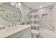 Beautiful bathroom featuring a shower over tub with neutral tile surround, modern vanity, and circular mirror at 5872 Monroe Rd, Venice, FL 34293
