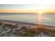 Coastal view of a serene beach at sunrise with gentle waves, lush vegetation, and distant horizon at 600 Gardens Edge Dr # 613, Venice, FL 34285